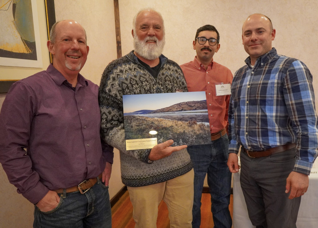 A photo of Karl Wenner receiving an award with Dave Smith to the left and Ed Contreras and Ron Leathers to the right.